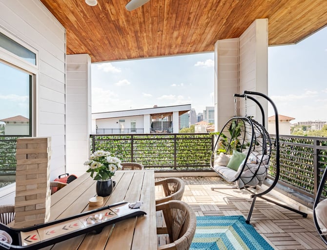 Rooftop terrace with wooden ceiling, dining table, hanging egg chair, and city skyline views